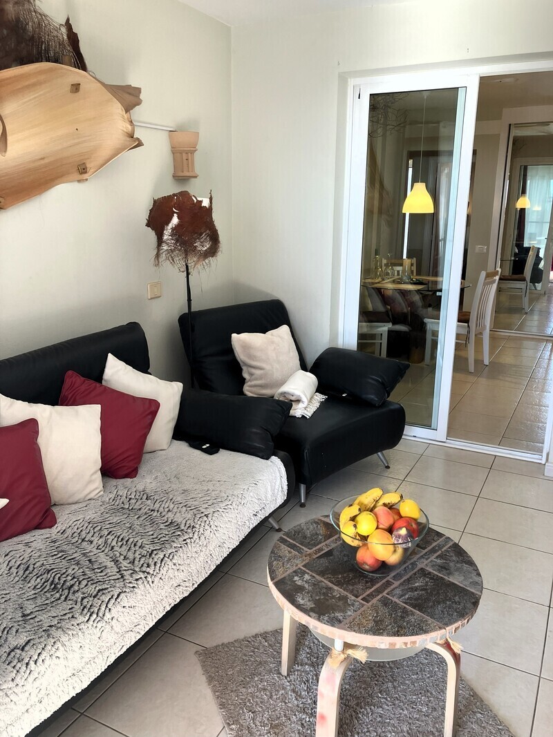 Living room with sofa, large smart TV and work desk.