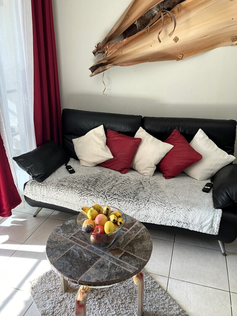 Living room with sofa, large smart TV and work desk.